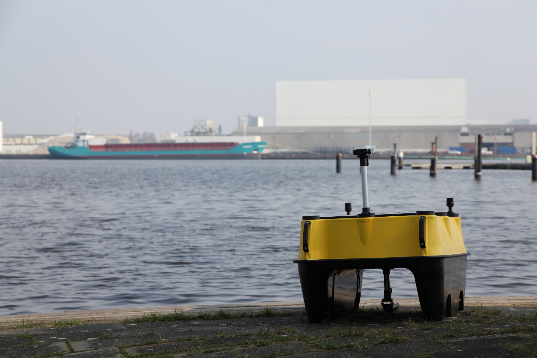 SensorBoat auf einer Kaimauer im Bremerhavener Hafen, im Hintergrund ein Frachtschiff